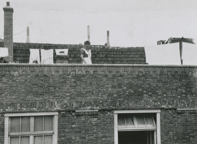 874835 Afbeelding van het dienstmeisje van de familie Van Doesum, dat de was ophangt op het dak van het pand Vredenburg ...